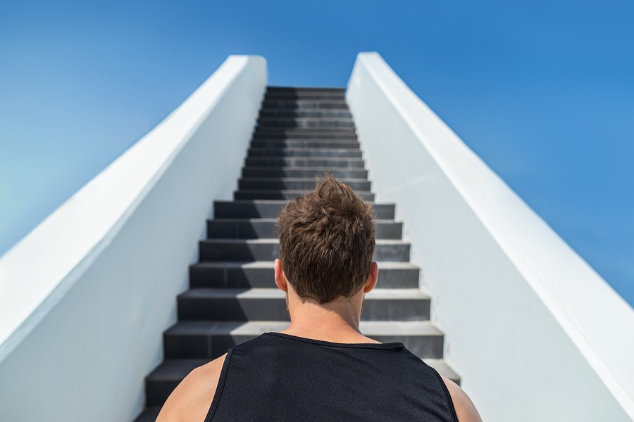 Fitness man looking ahead at stairs climbing challenge. Runner going up running staircase for cardio